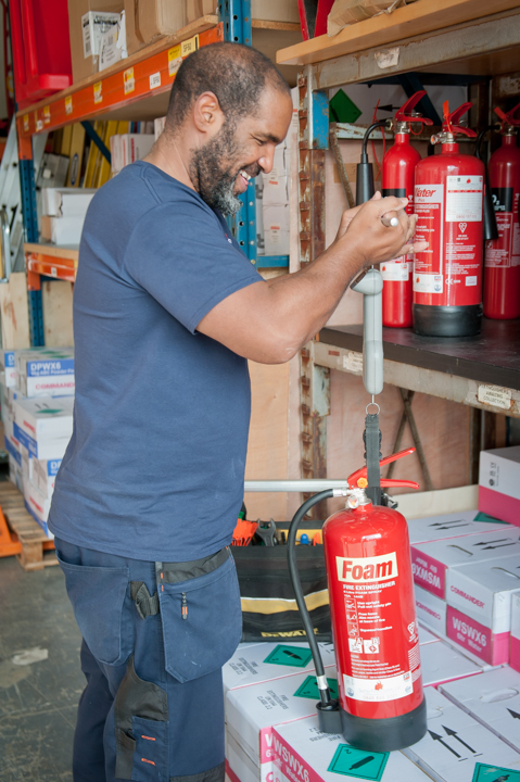 Fire extinguisher servicing: engineer weighing a fire extinguisher.